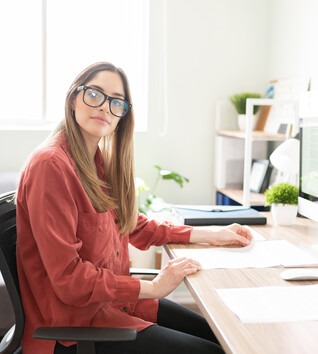 Person with glasses sitting at a desk with a computer
