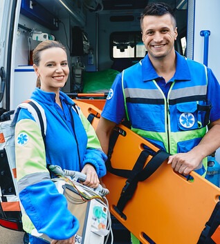 Two people in emergency uniforms standing in front of ambulance