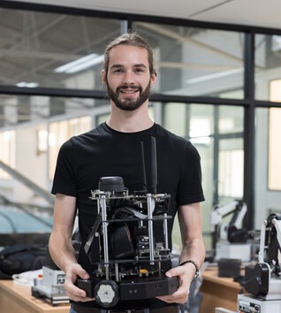 Man holding mechatronics equipment and smiling at the camera