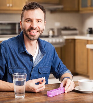 Male sitting at a table with a daily pill tracker