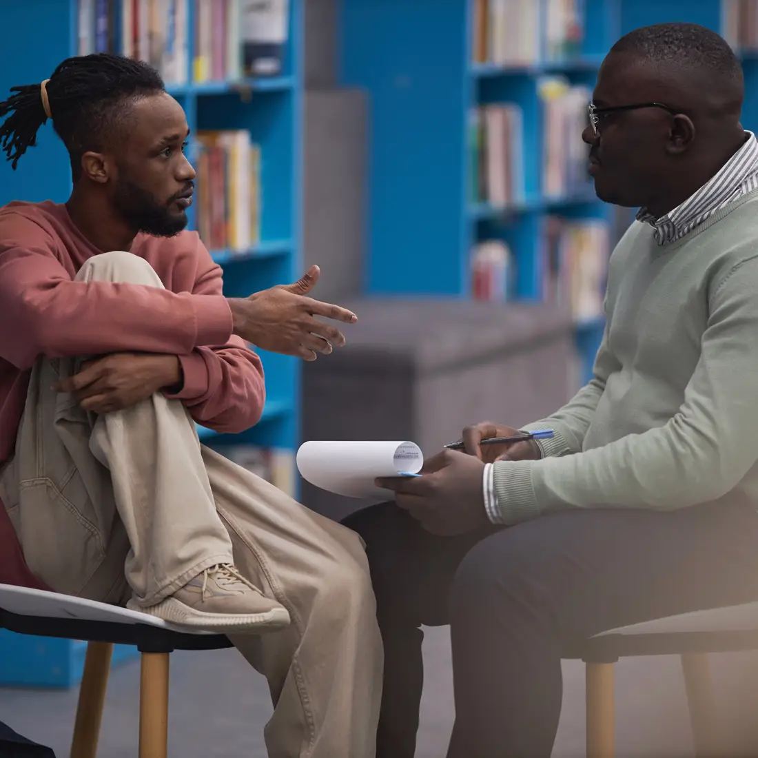 Two people sitting in chairs, talking