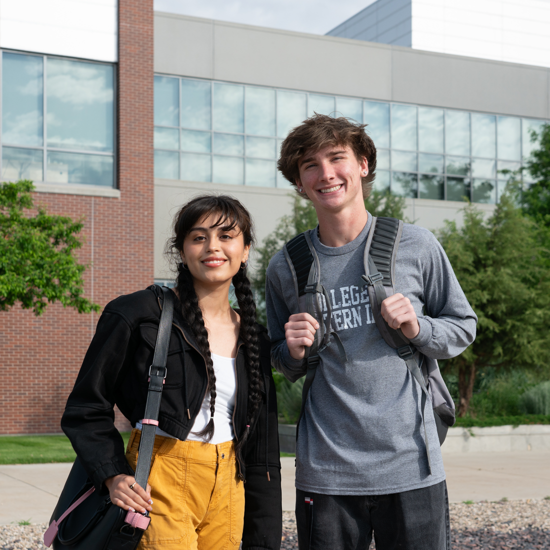 Two students with bags standing outside building