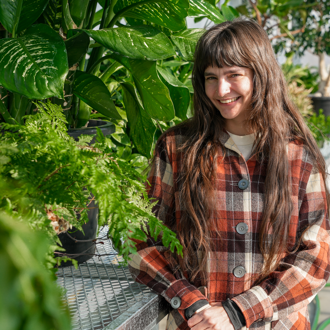 Student stands in greenhouse in front of several plants