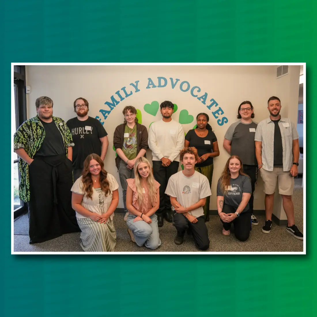 Group of 11 people stand and kneel in front of sign that says Family Advocates | Green back drop behind image