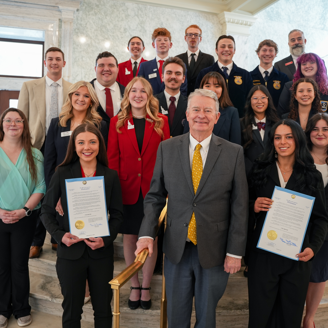 Group of people standing on staircase, with two people holding a proclamation