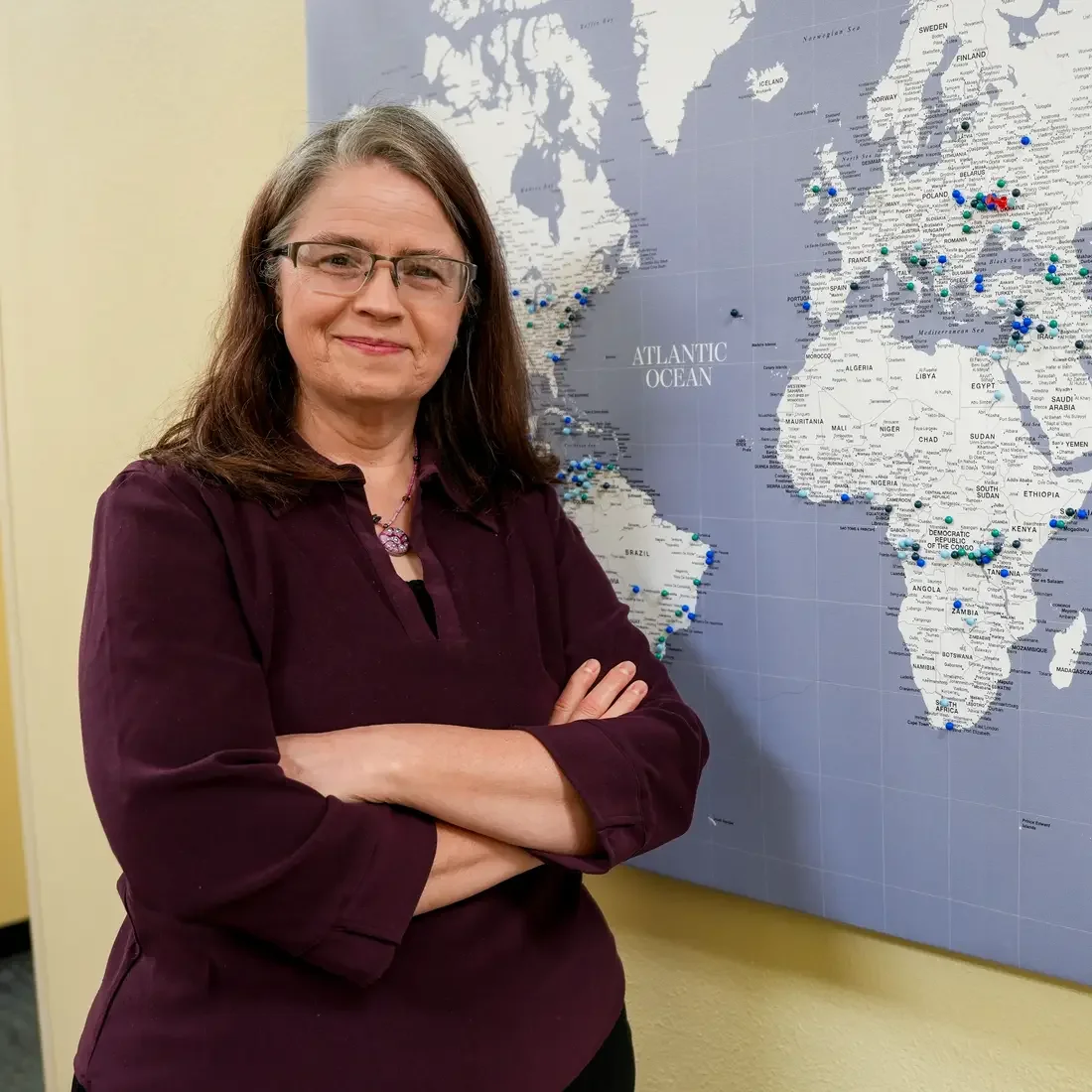 Holly Bazarski stands in front of world map