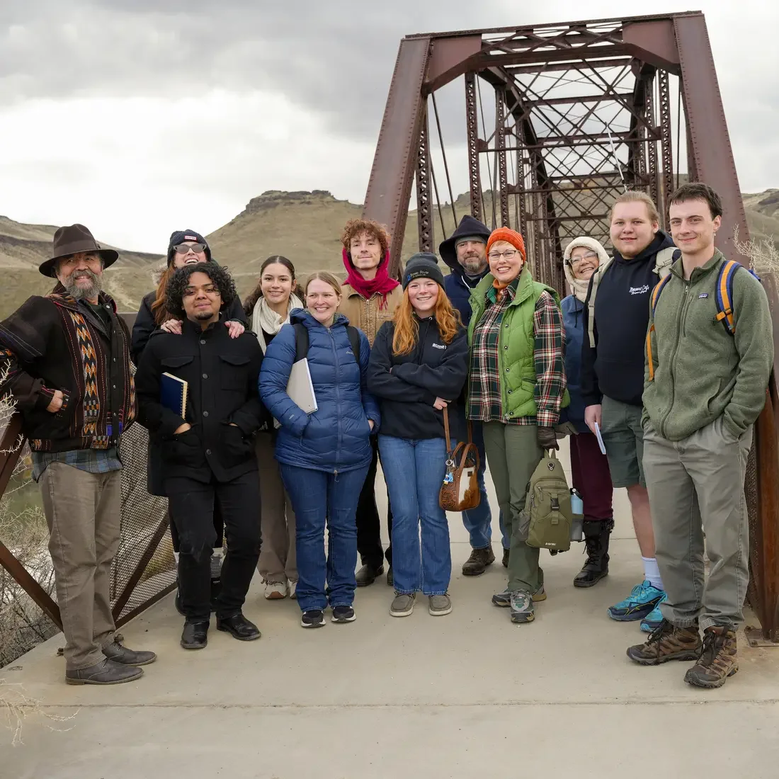 Group of people stand in front of a bridge
