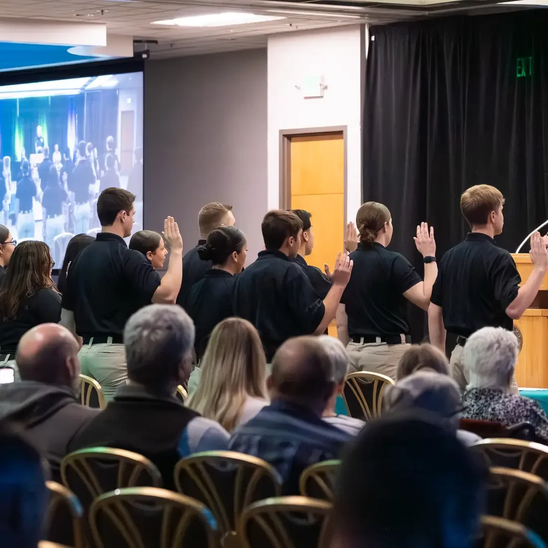 Graduates raising their right hand in audience