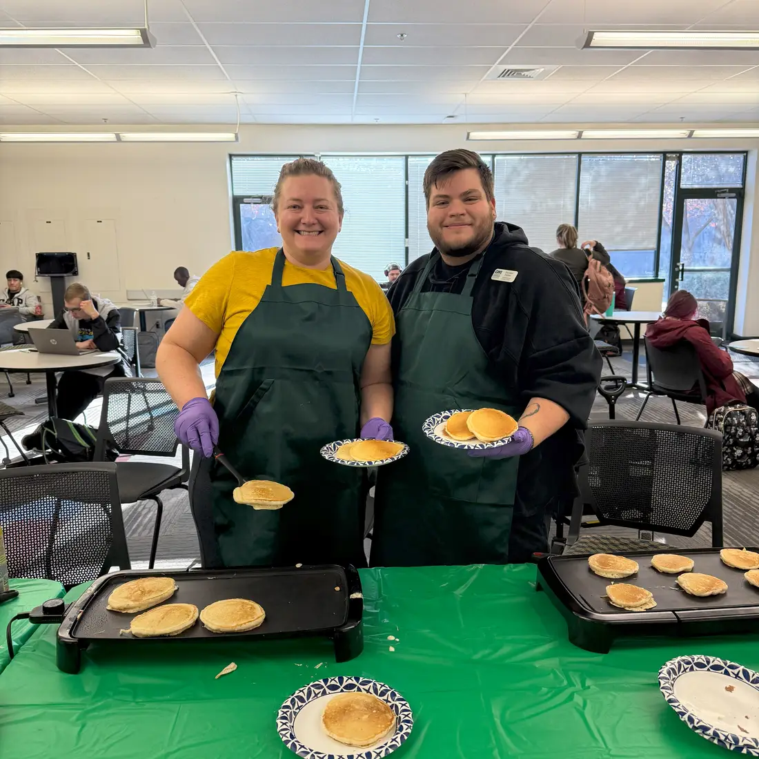 Two people holding plates of pancakes