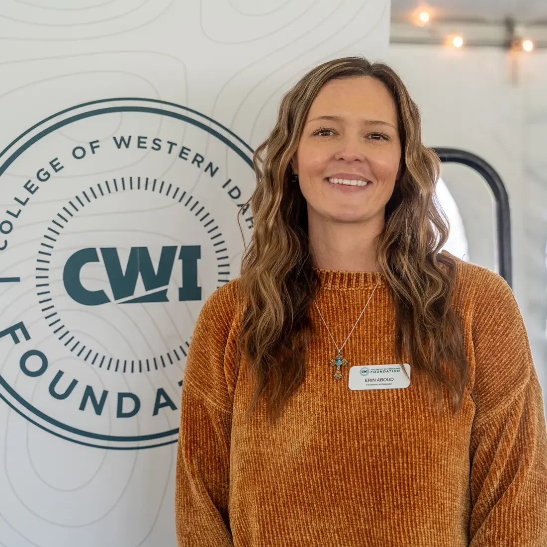 Erin Aboud stands next to CWI banner