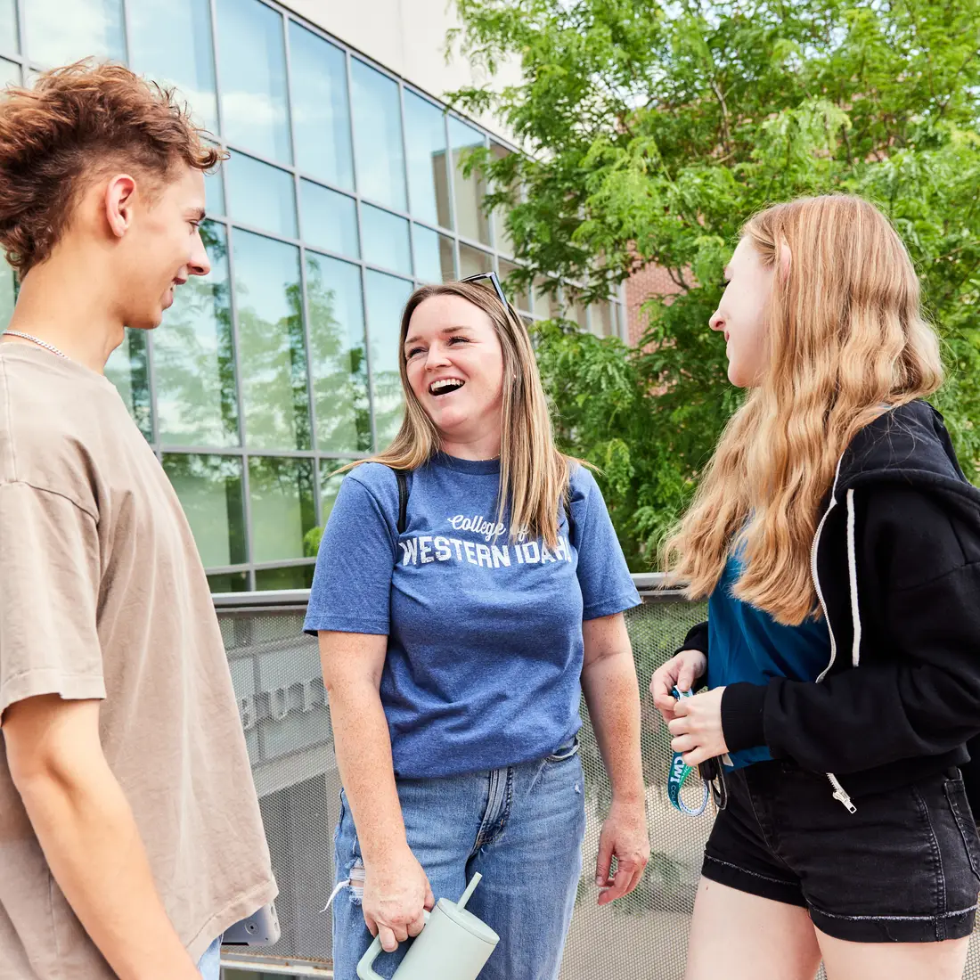 Three students stand near railing and laughing