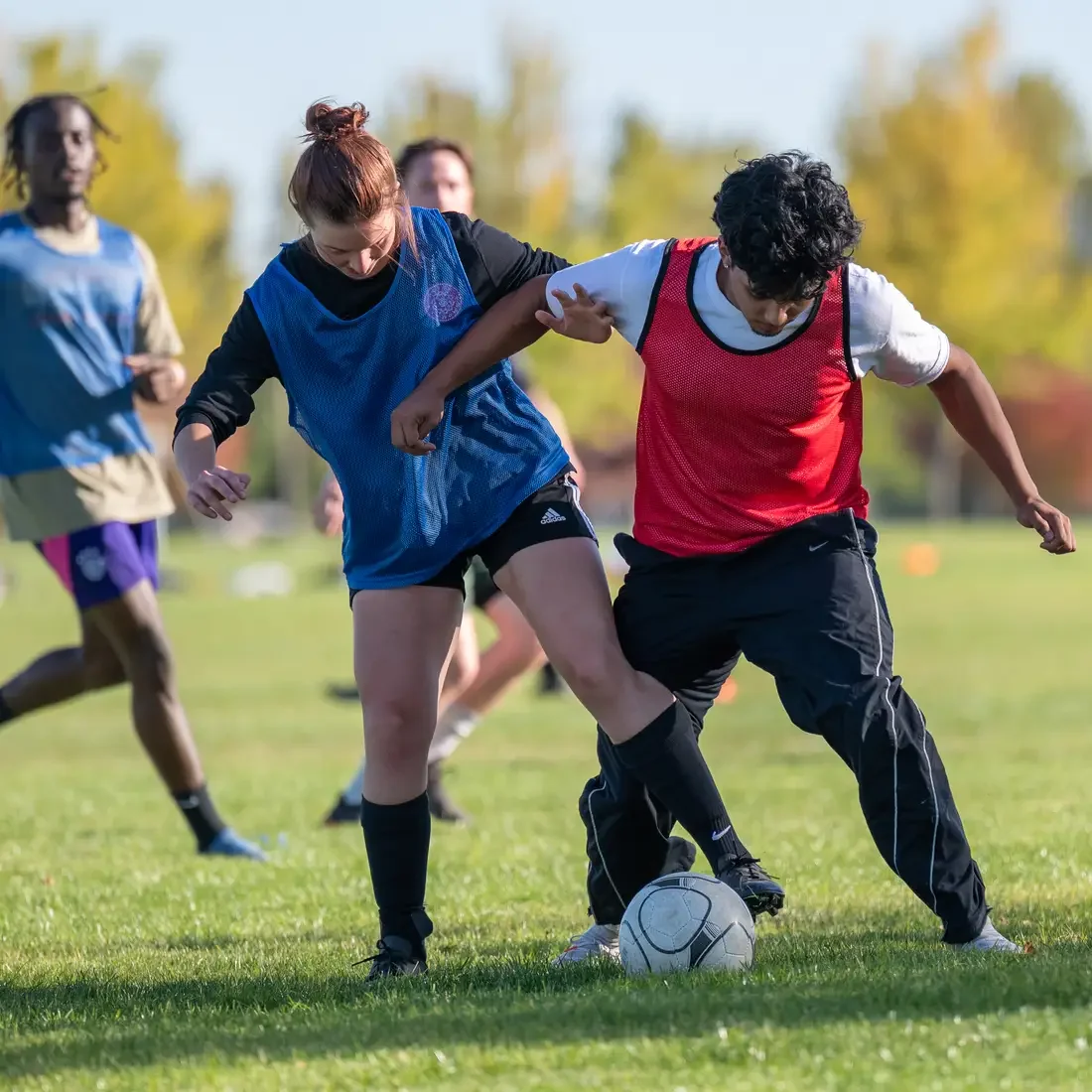 Two players kicking a ball with two others in the back