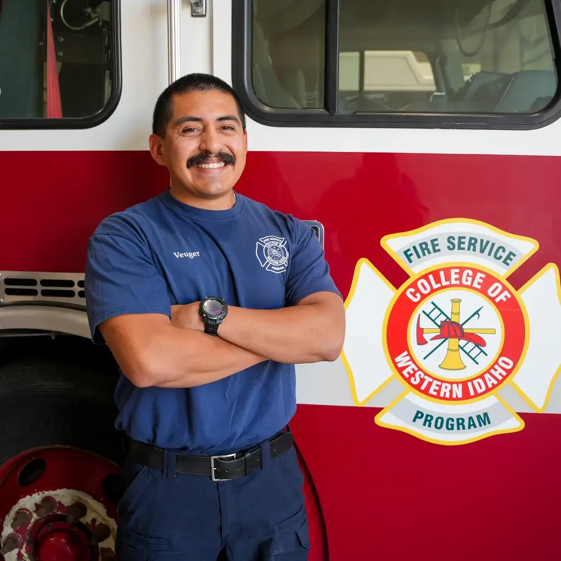 Ryan Veuger stands in front of fire truck with CWI fire academy logo