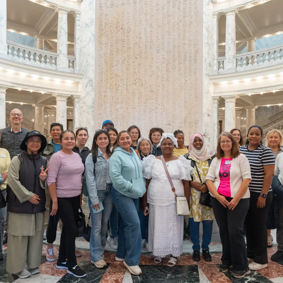 Group of people stand together in front of large signed document in Capitol rotunda