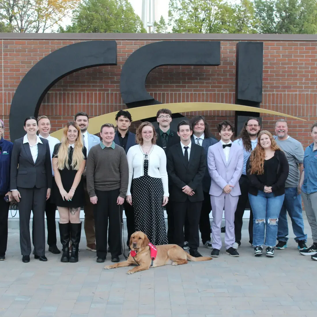 Students stand in front of CSI logo