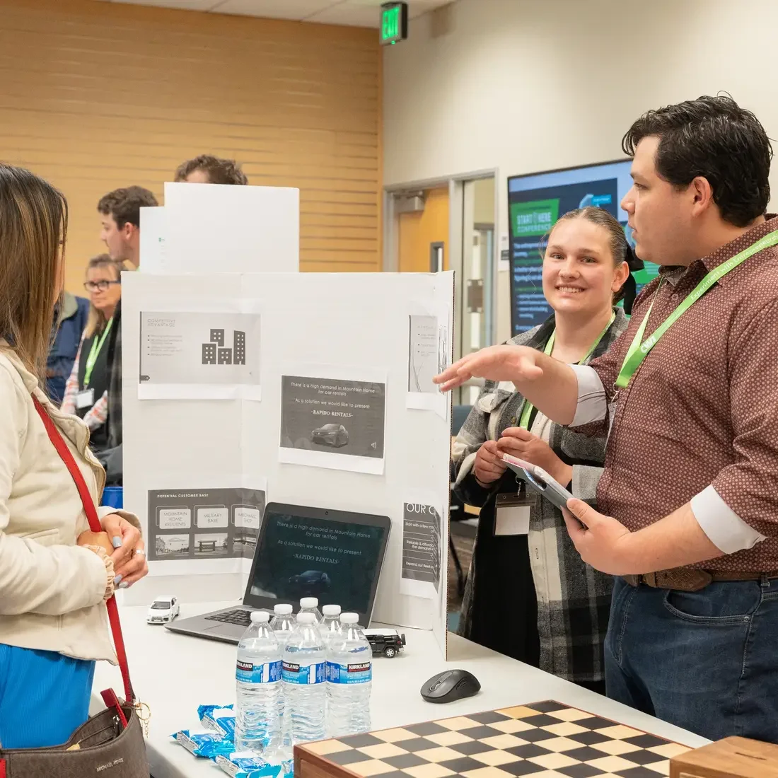 Person stands next to presentation board chatting with another person