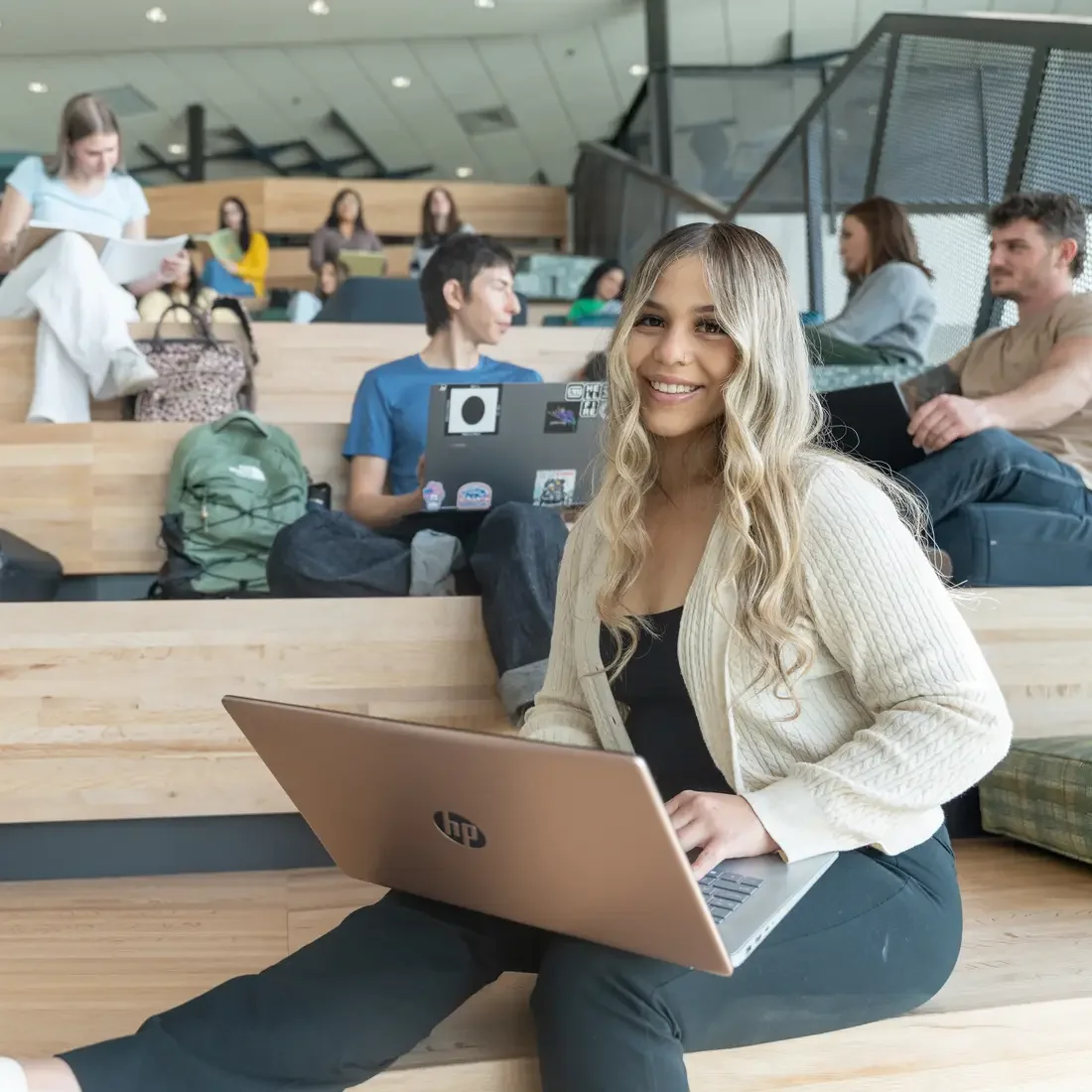 Person sits with computer on lap, with others behind them