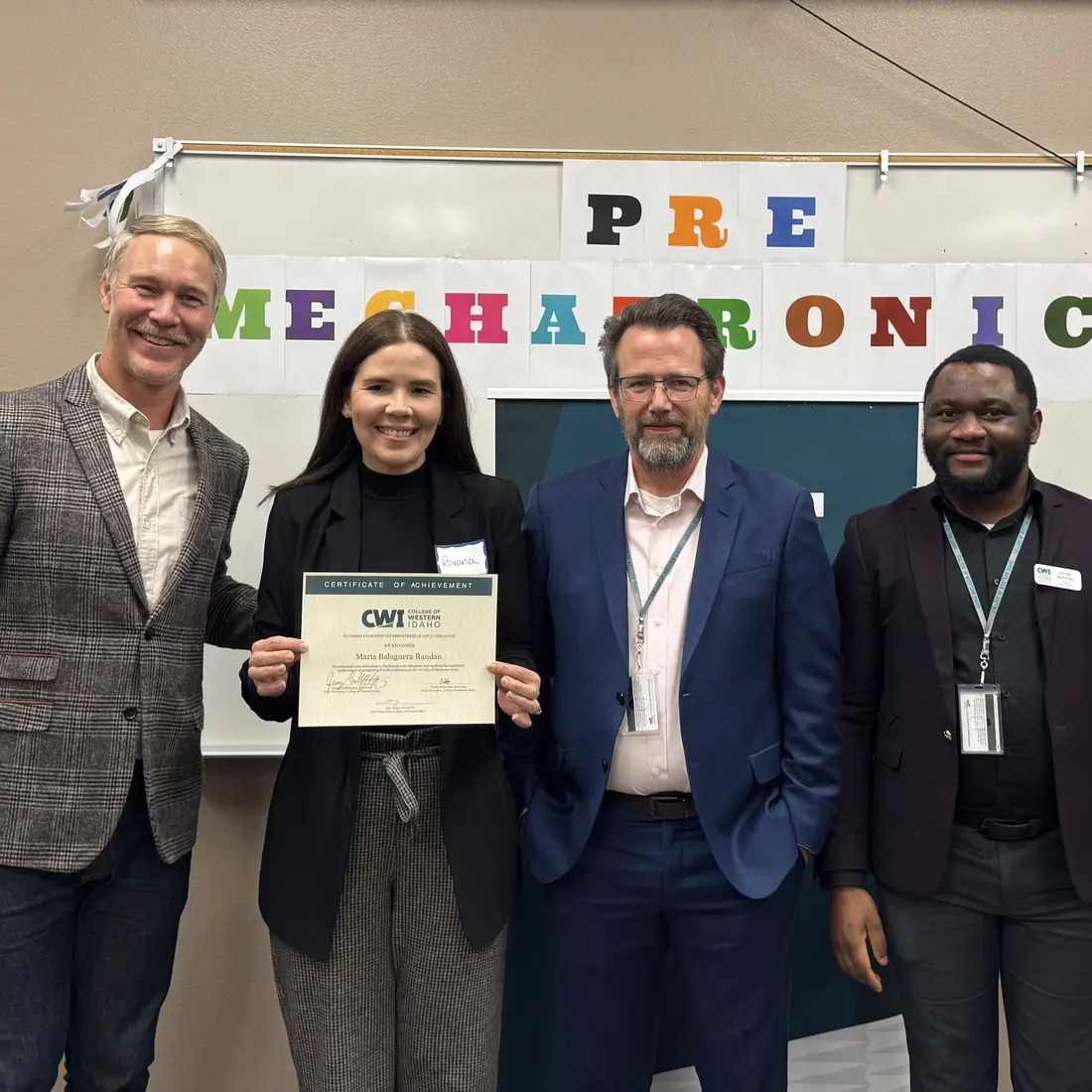 Roxana holding a certificate with three faculty standing beside her