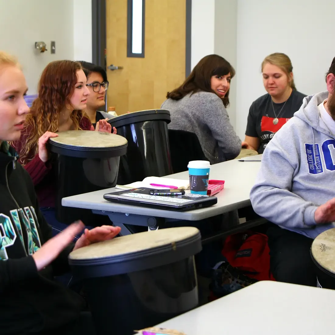 Students using buckets and drum heads in music class.