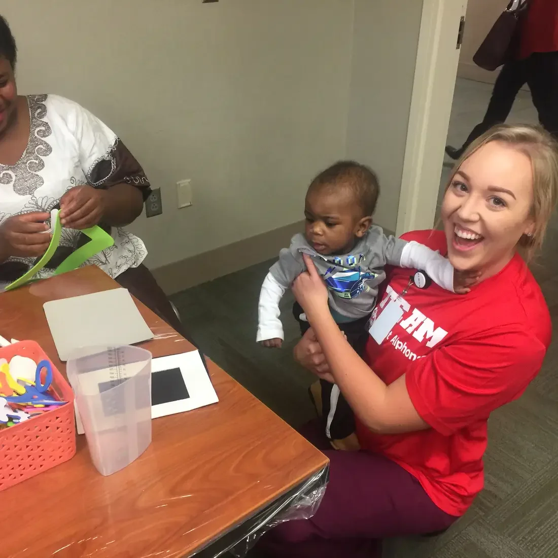 Nursing student volunteering with mother and baby at St. Al's NICU