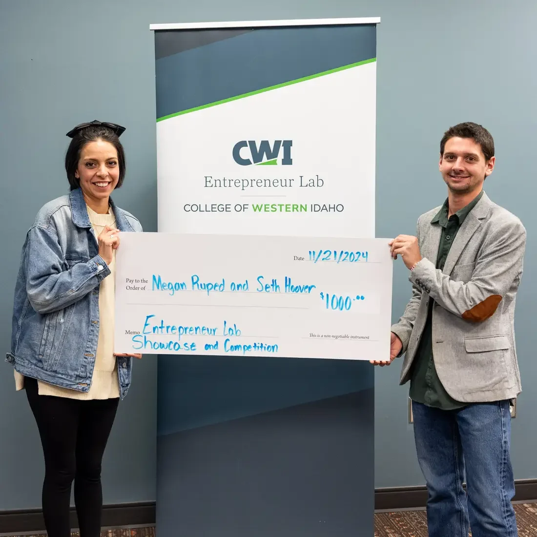 Two people hold a ceremonial check for $1000