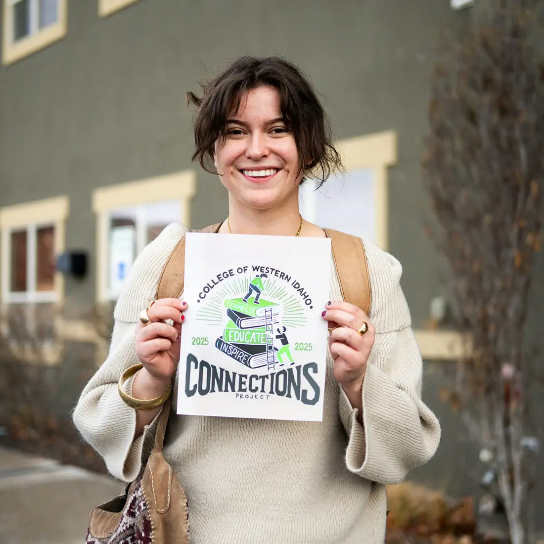 A smiling student holds a paper with a printed graphic.