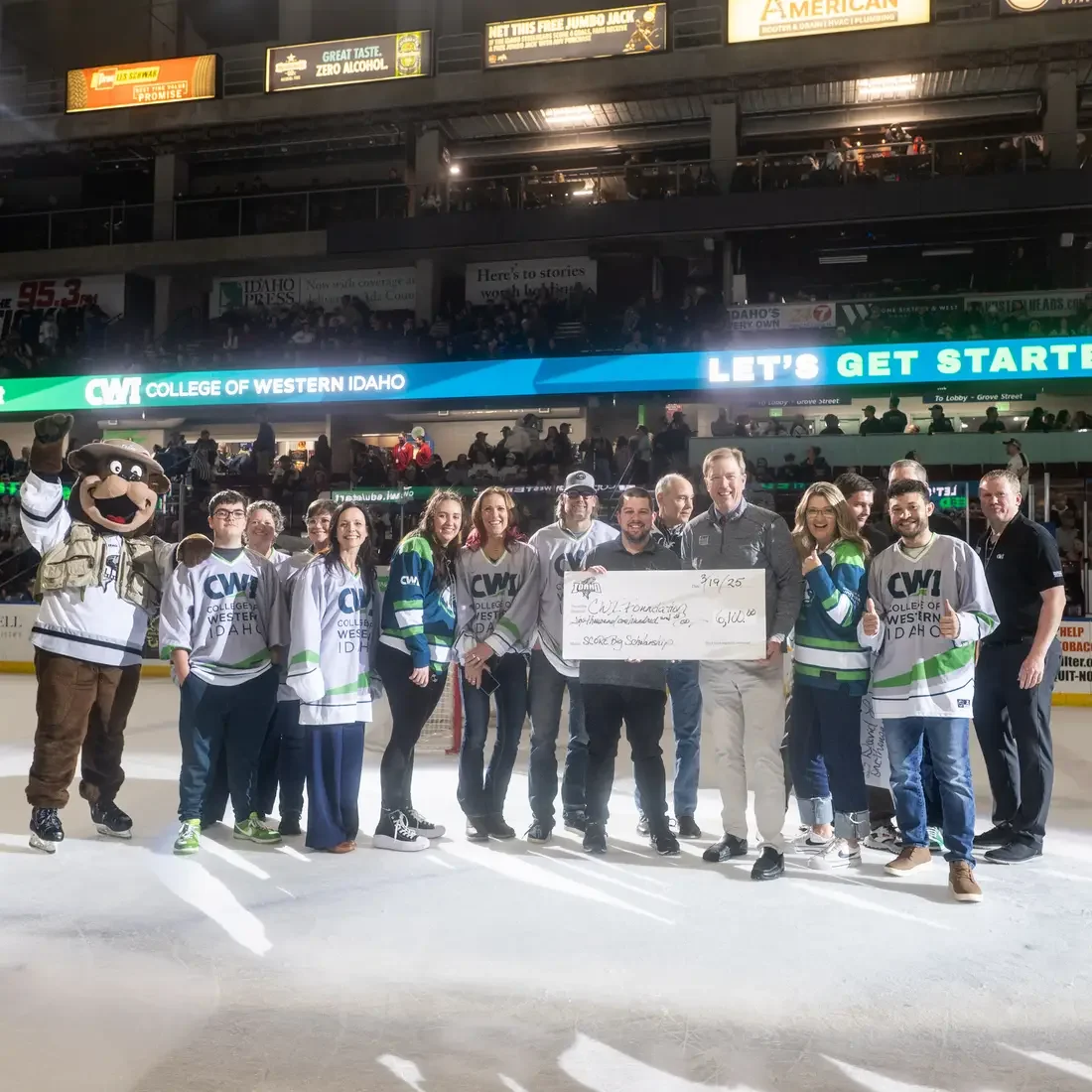 People pose for a photo holding a ceremonial check on the ice of a hockey game. 