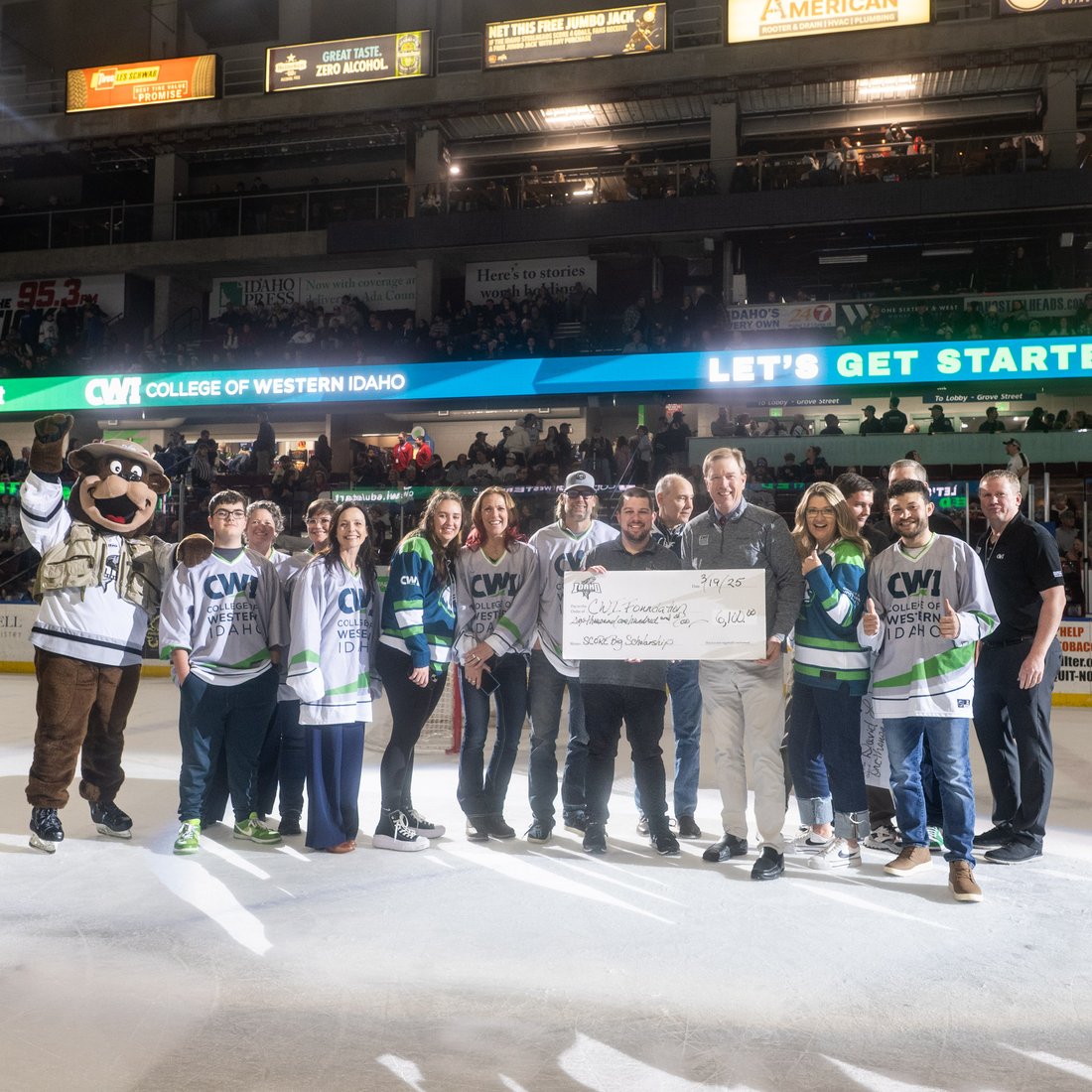 People pose for a photo holding a ceremonial check on the ice of a hockey game. 