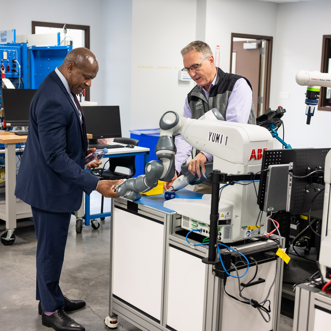 SUNY Oswego president Peter Nwosu inspects a robotic arm in the CWI Mechatronics Lab during a tour with Micron representatives.