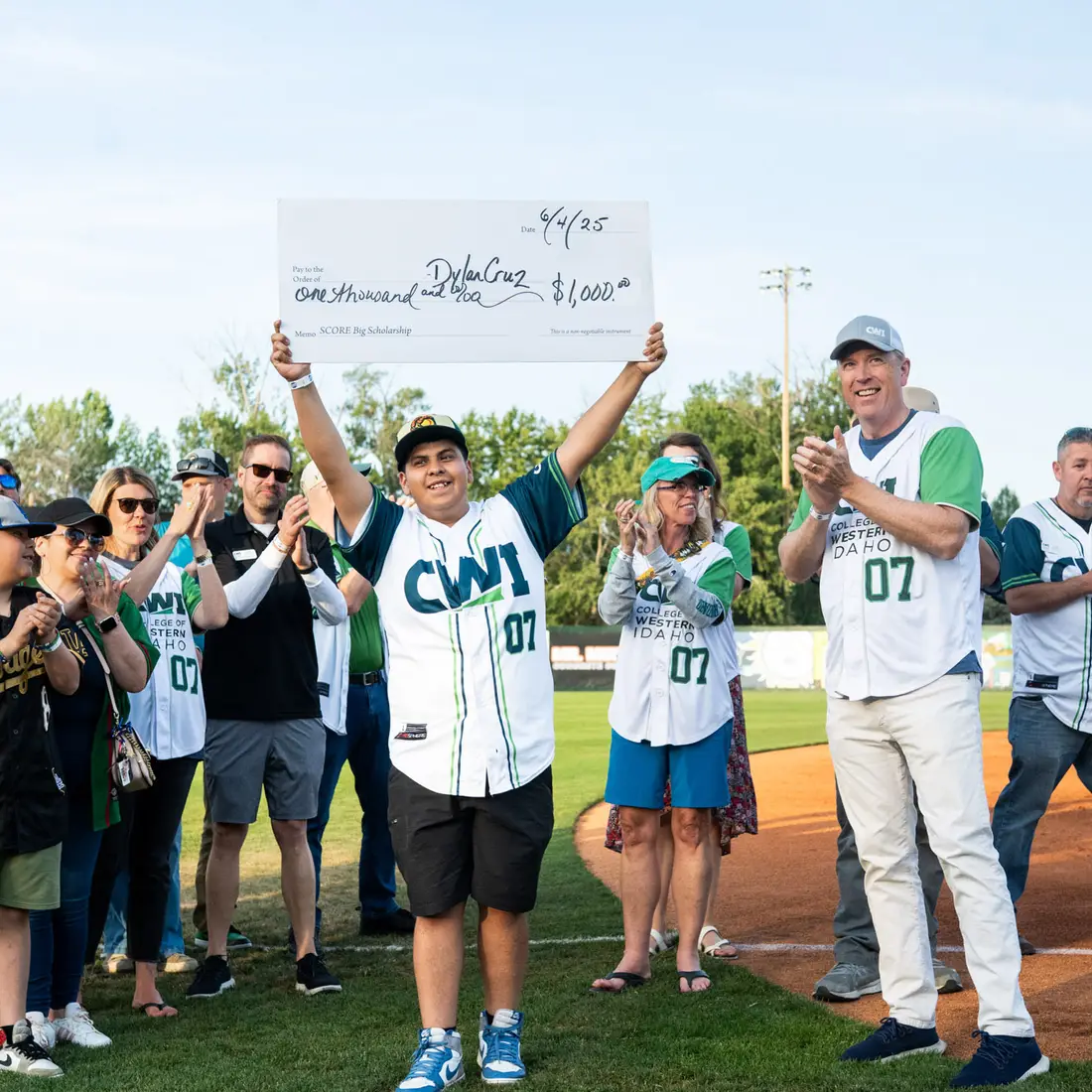 A boy holds up a ceremonial check at a baseball game.