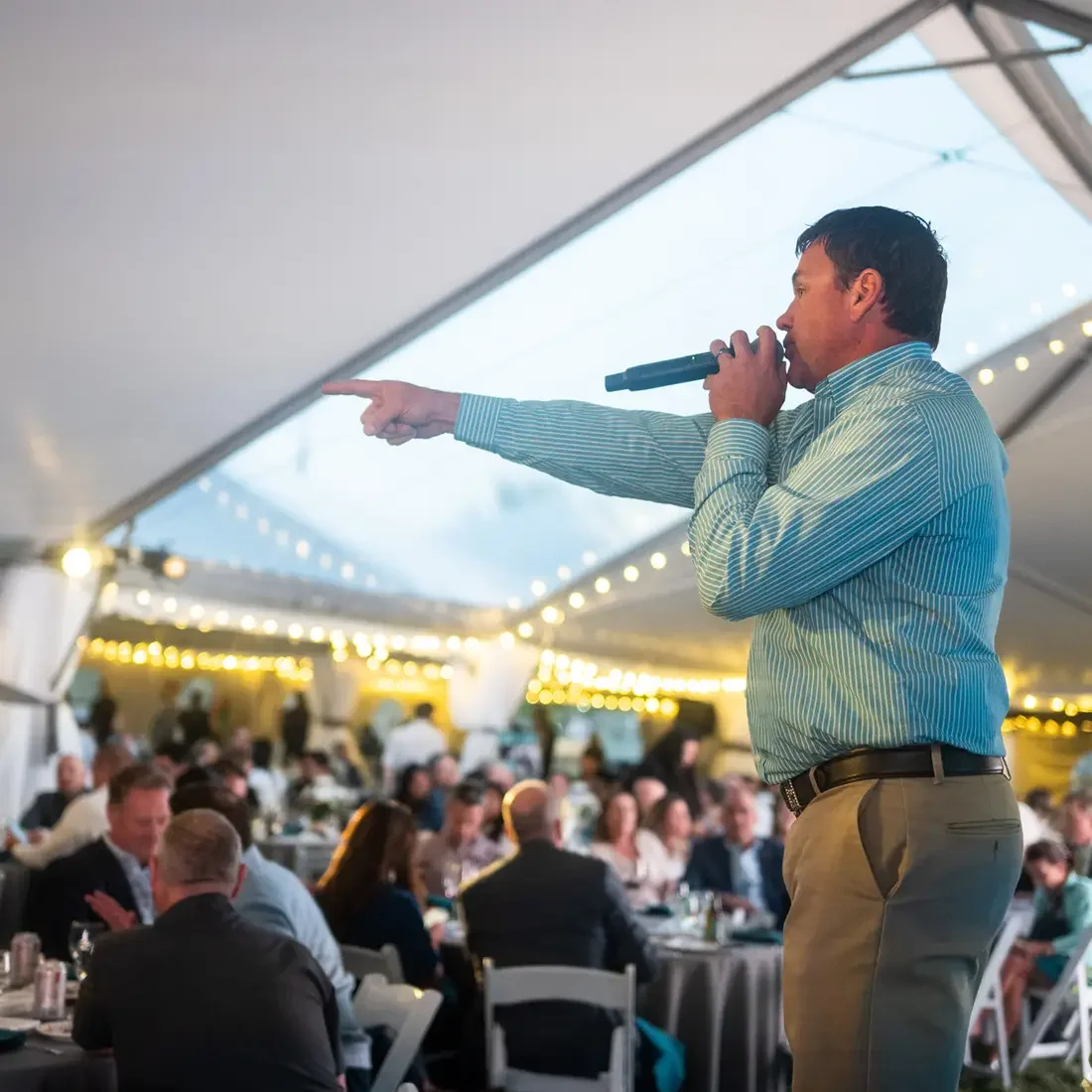 A live auctioneer points to the audience during a benefit auction.
