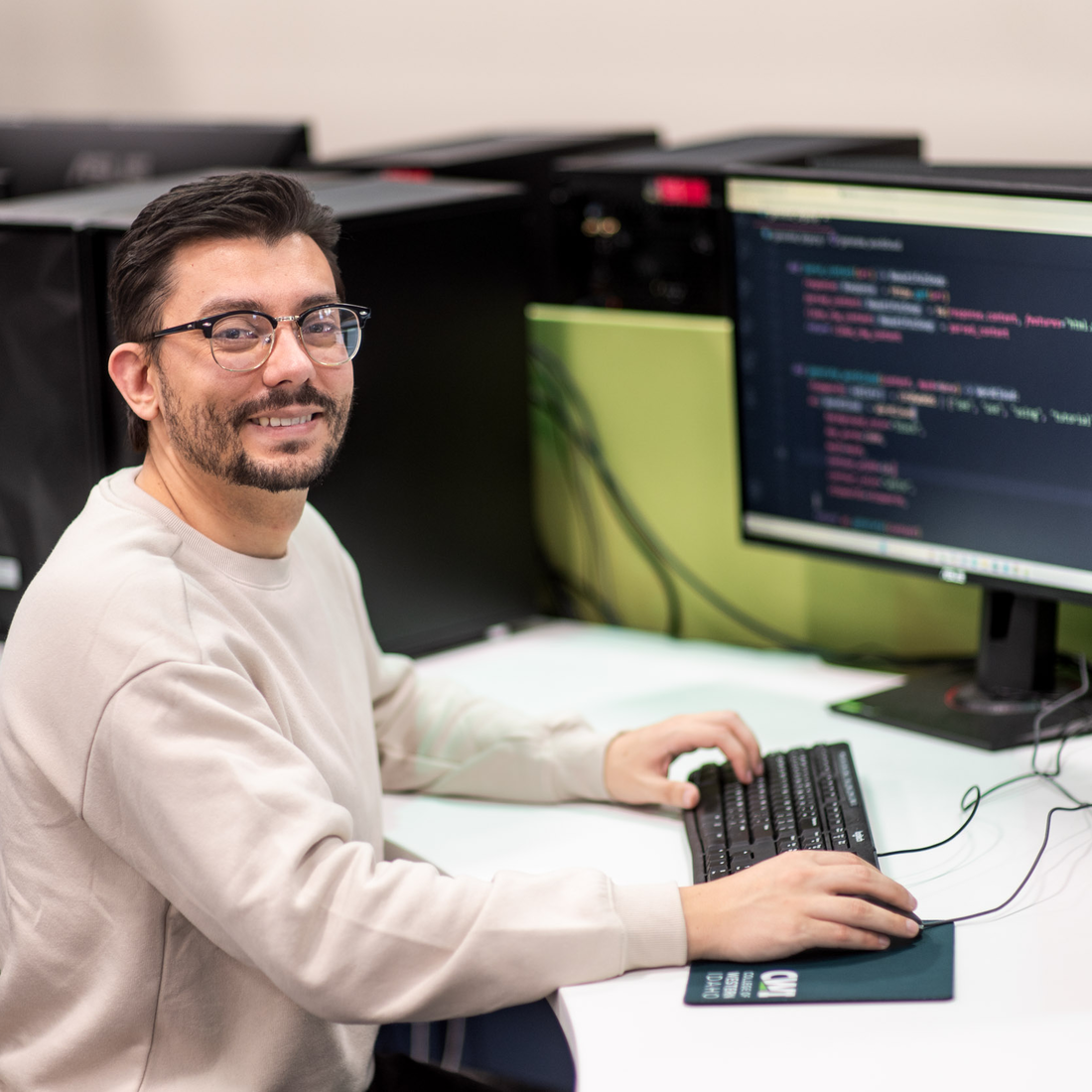 A software development student sits for a portrait at a computer.