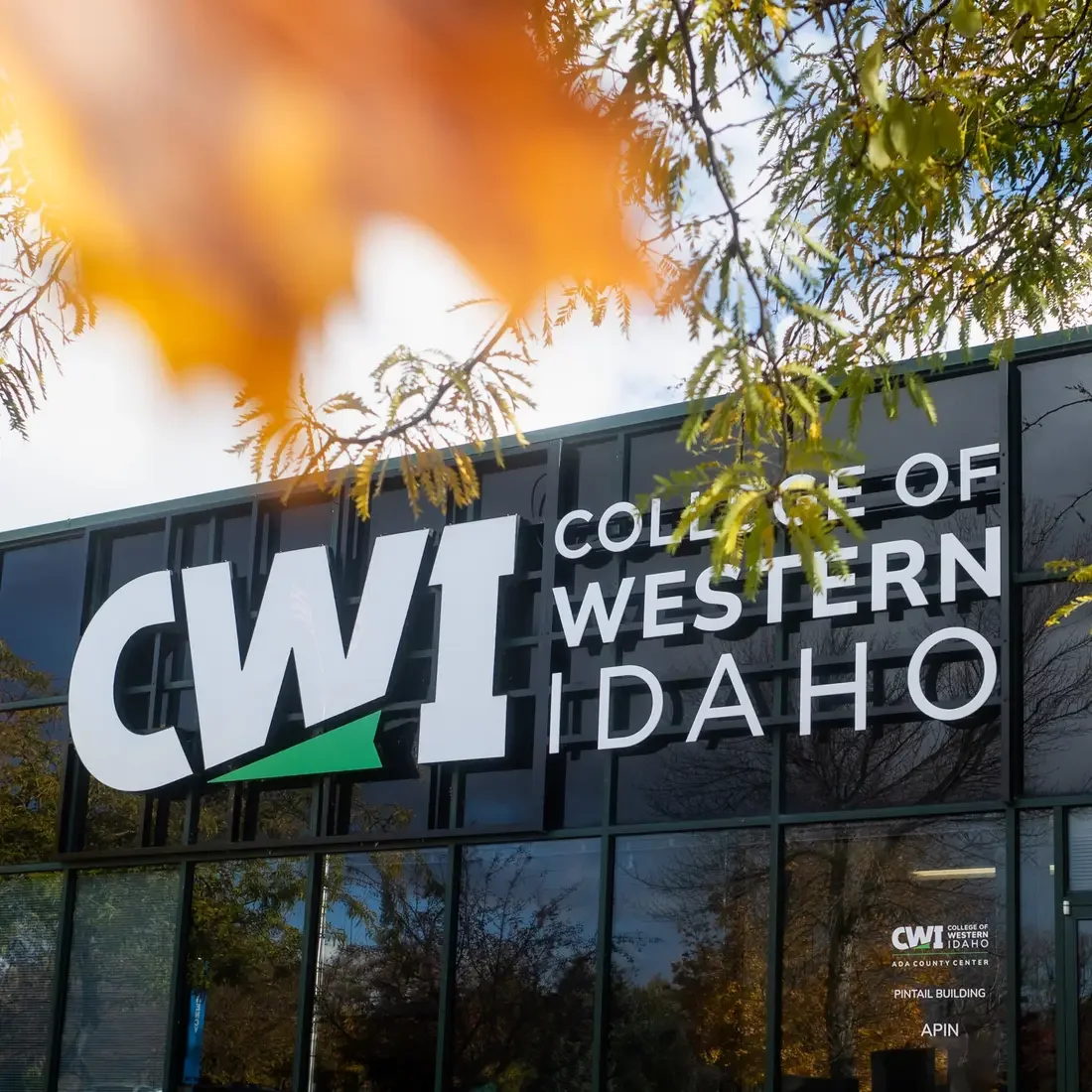 A photo of the CWI logo on a building, with Fall foliage.