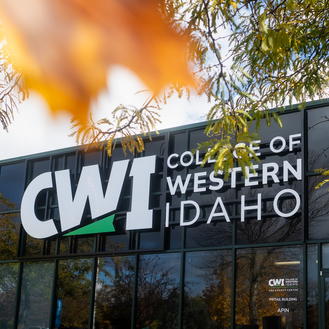 A photo of the CWI logo on a building, with Fall foliage.