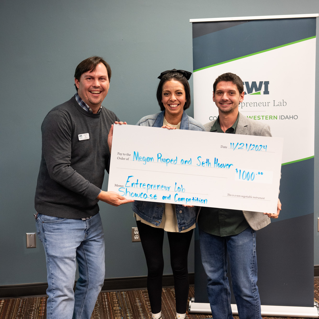 2 entrepreneurs are presenting with an oversized $1000 check.