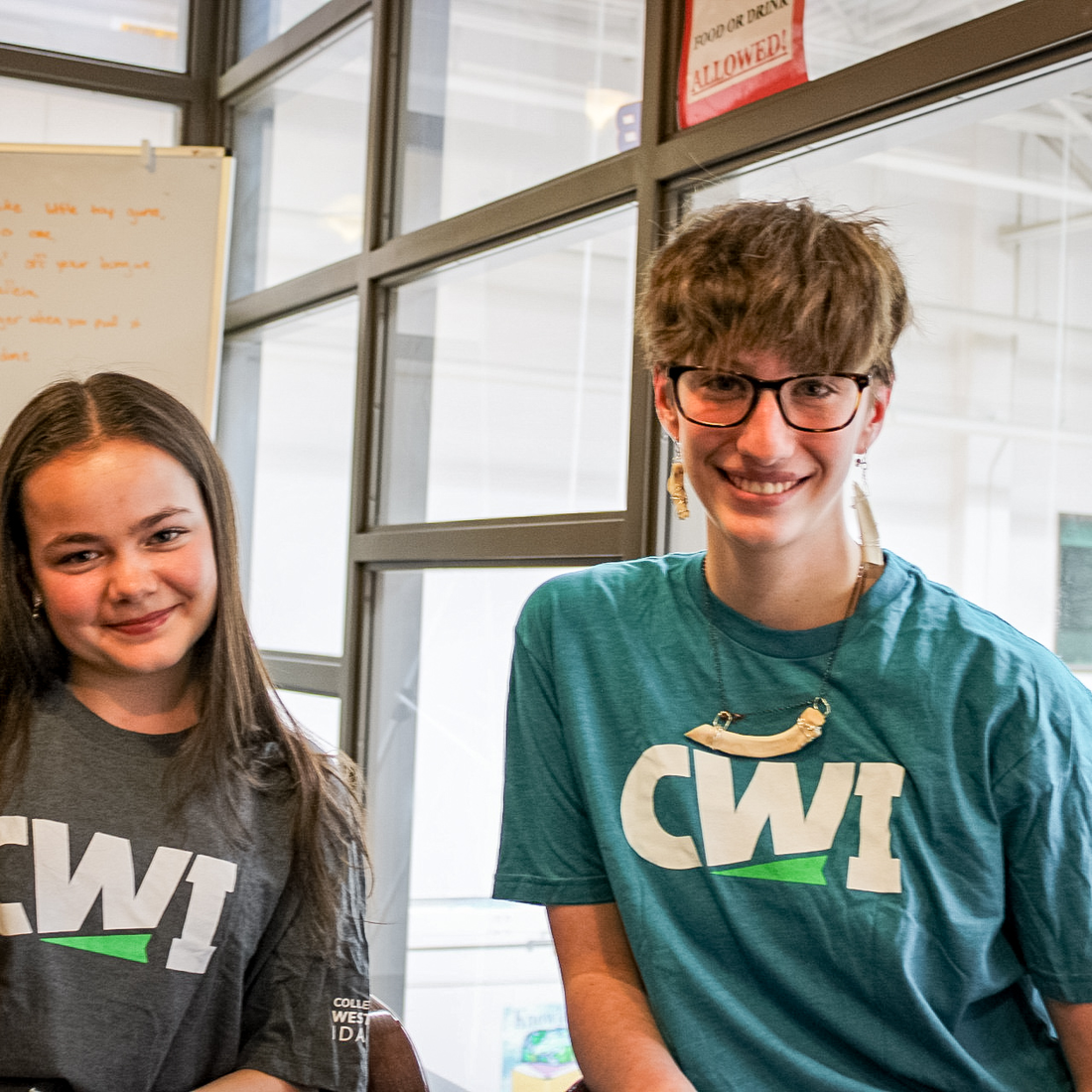 Two students wearing CWI t-shirts smile for a photo.