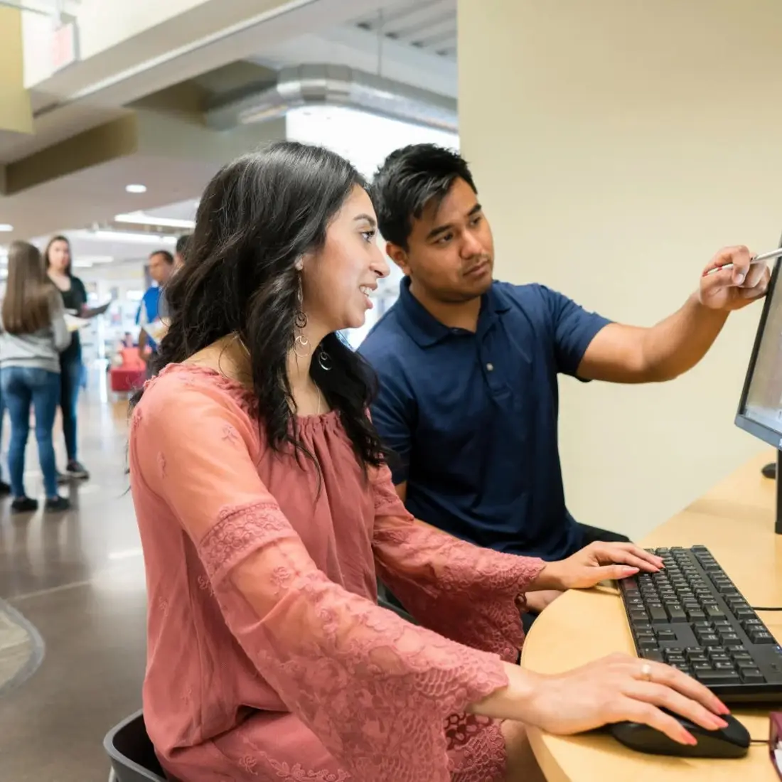 A student gets help at a computer from an advisor.