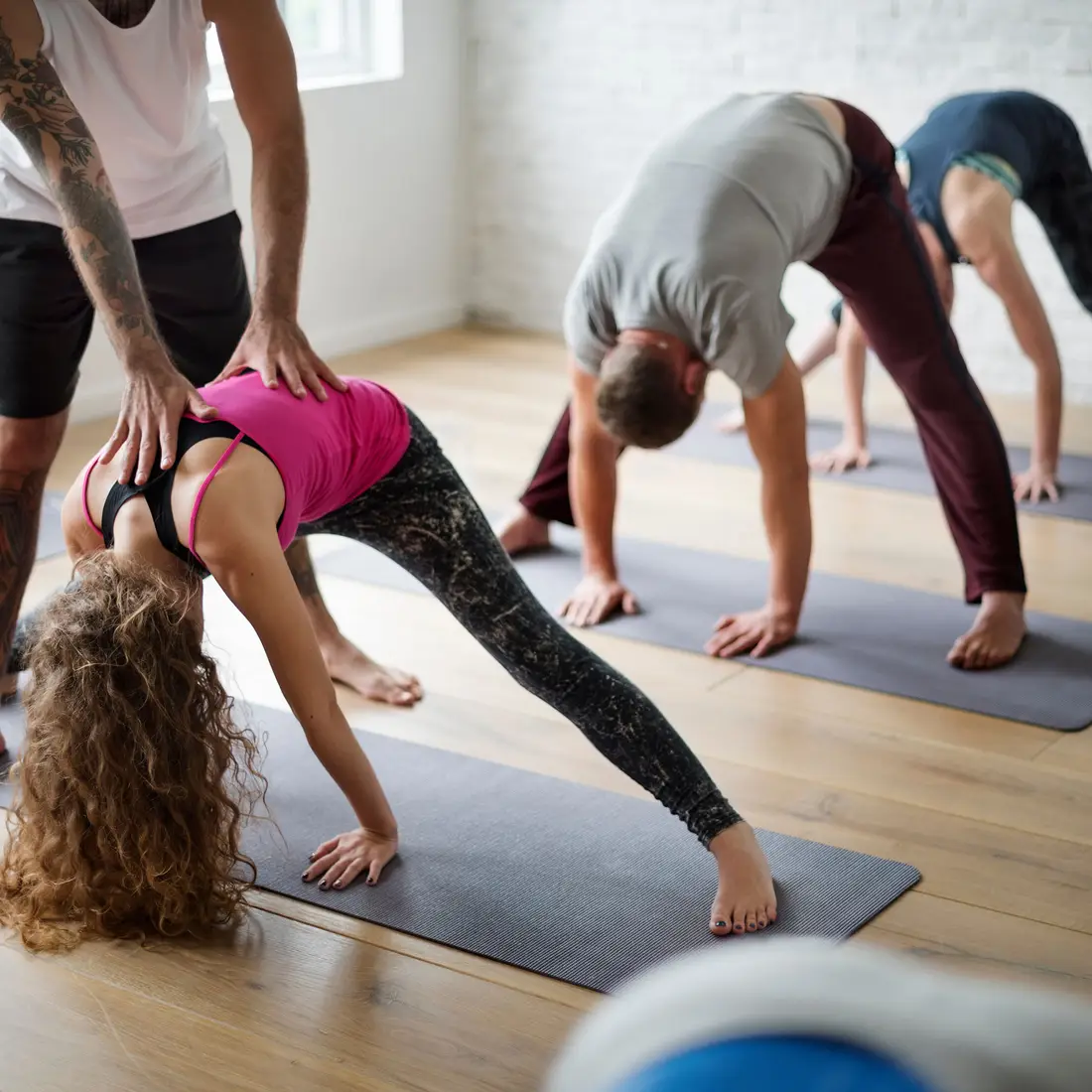 People stand on yoga mats as they stretch from the waist to touch the ground.
