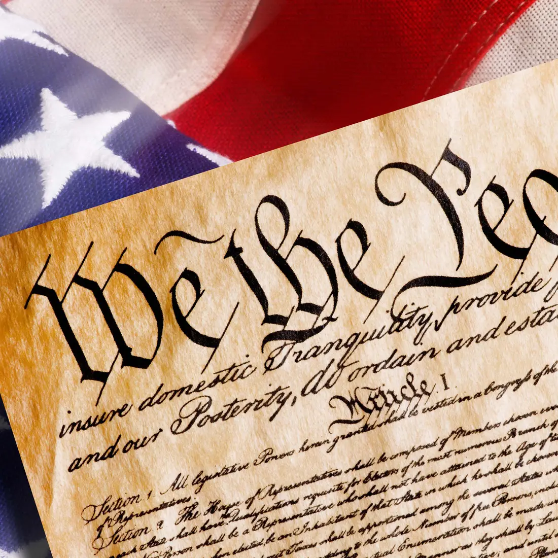 A composite image of the US Constitution over an American flag.