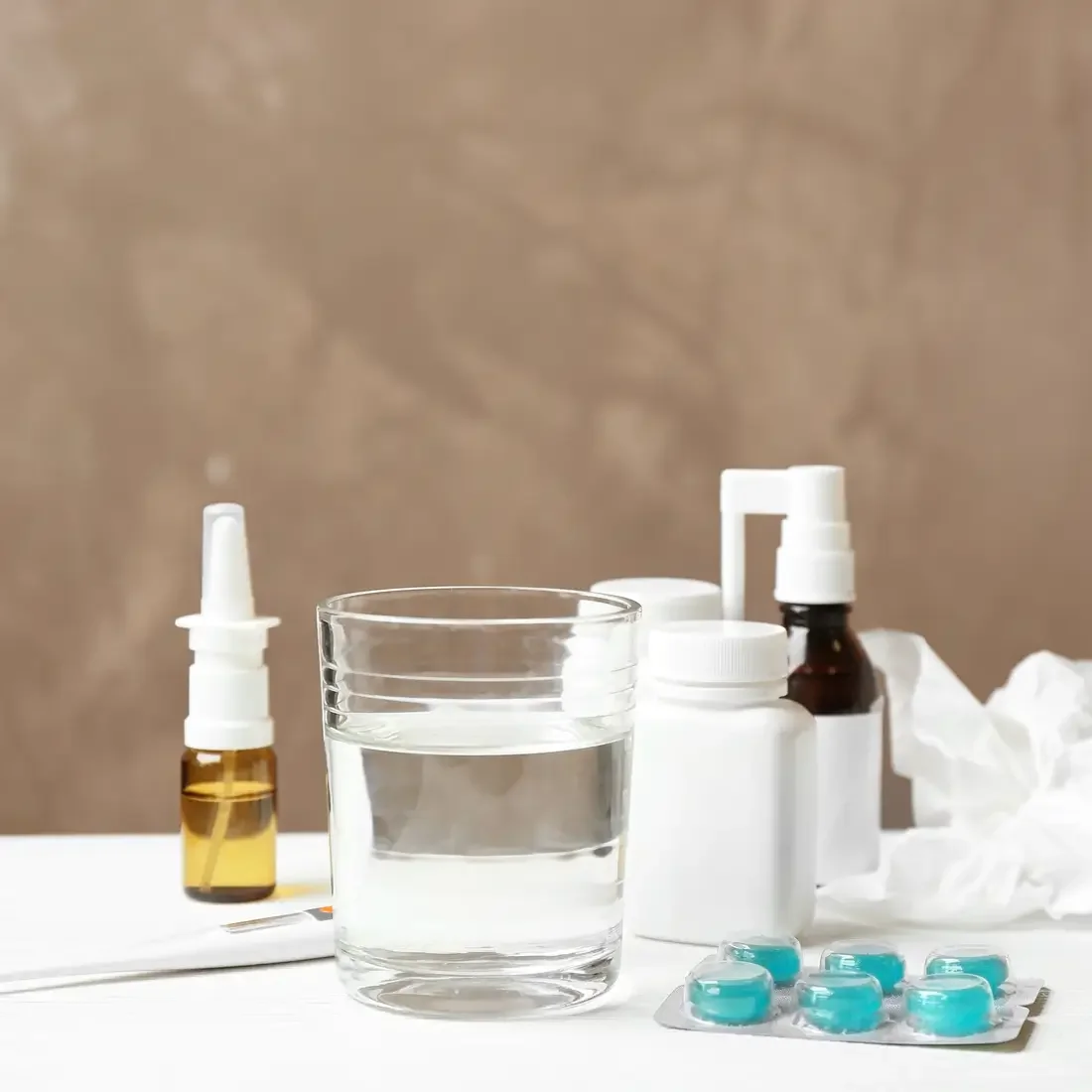 Glass of water, pills and drugs for cold on table