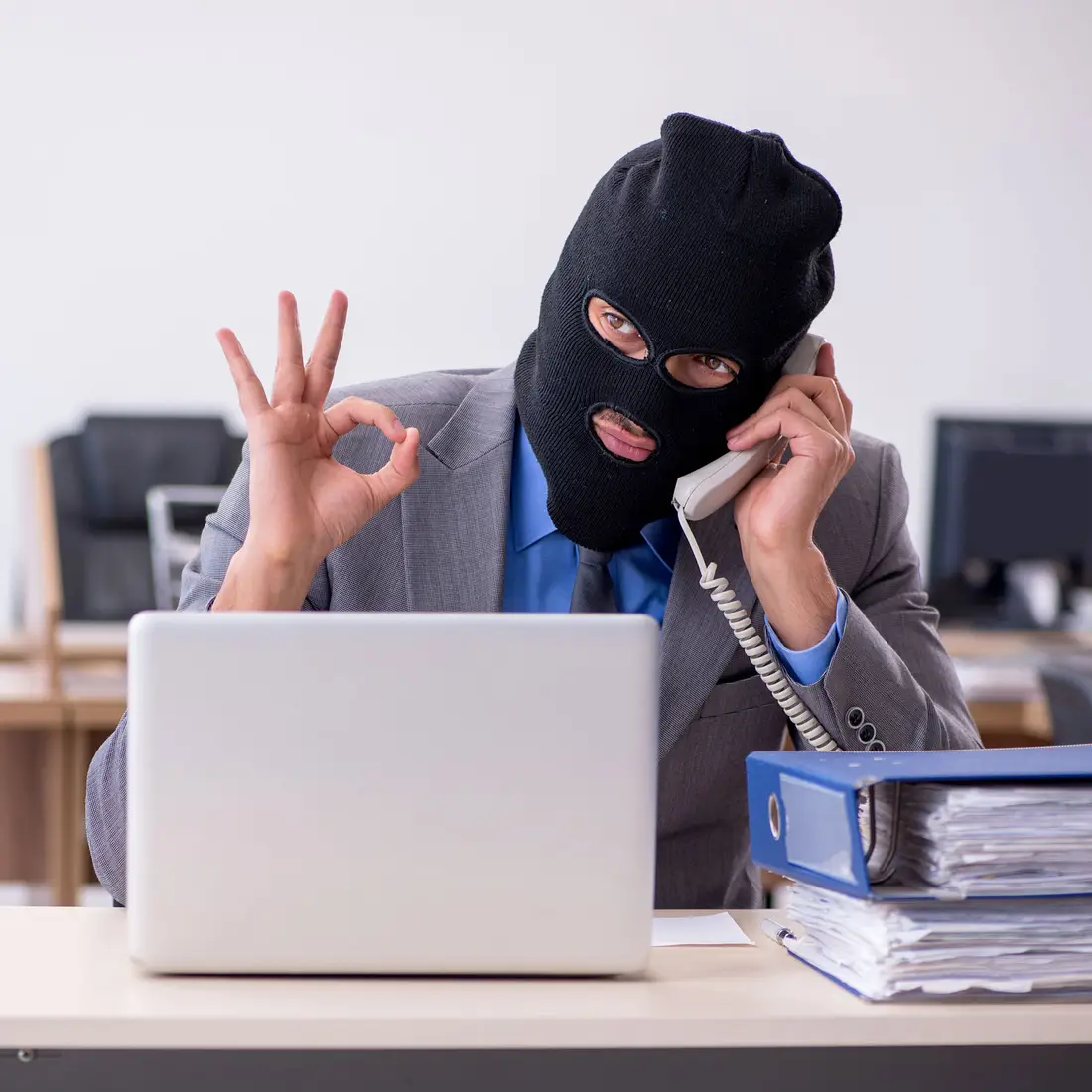 A photo of a masked man in front of a computer posing as a cyber criminal.