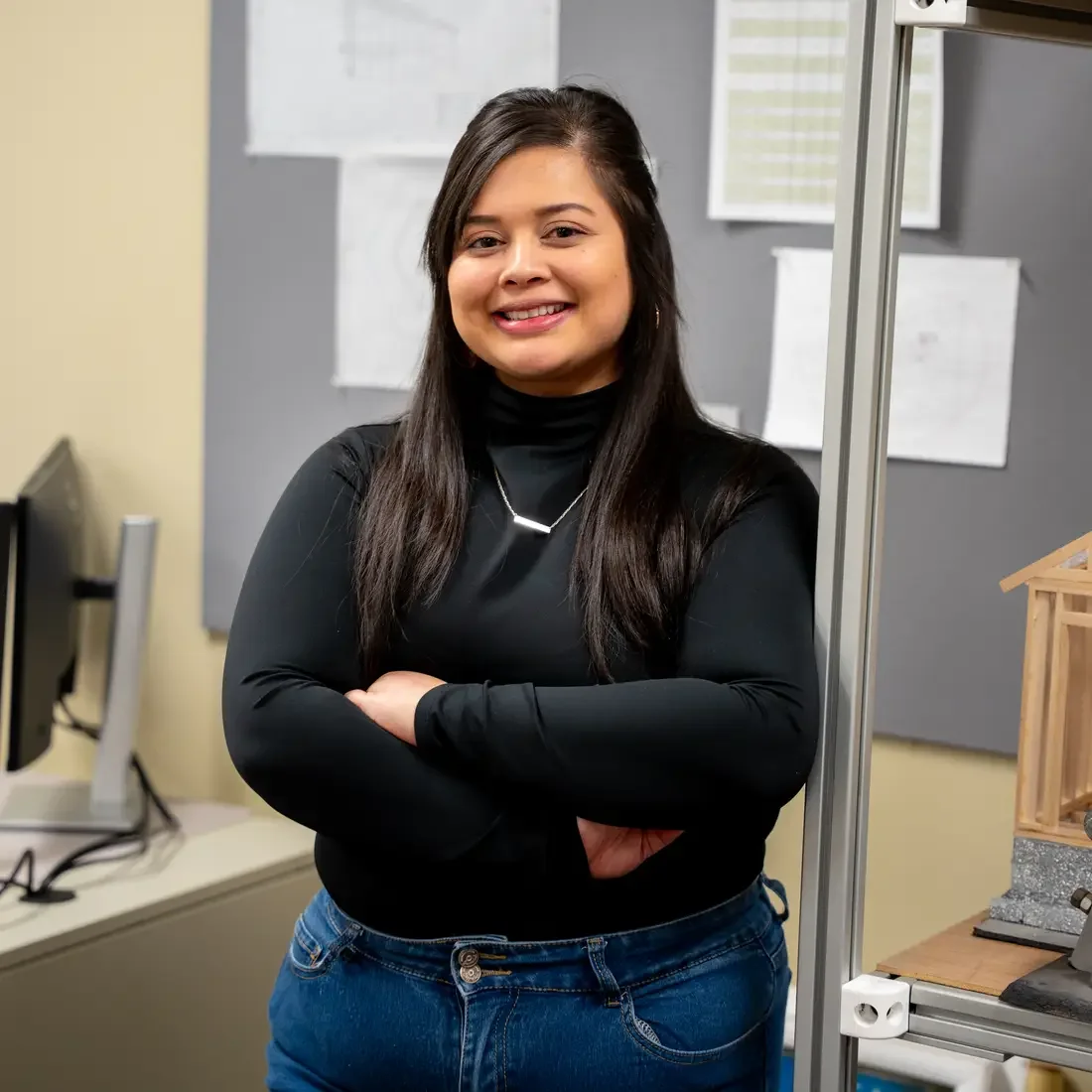 Student stands in front of billboard and next to shelving