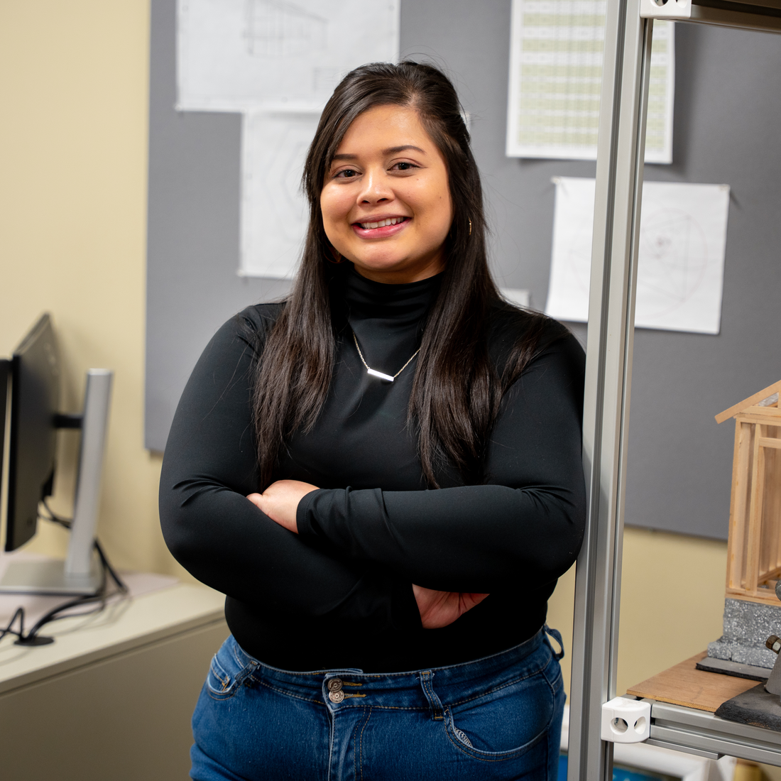 Student stands in front of billboard and next to shelving