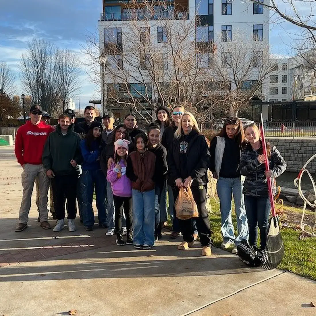 Group of people stand outside with rakes and lawncare equipment