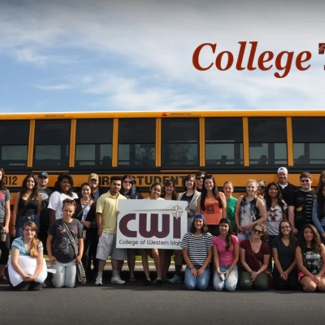 Large group of students holding a CWI sign and standing in front of a bus
