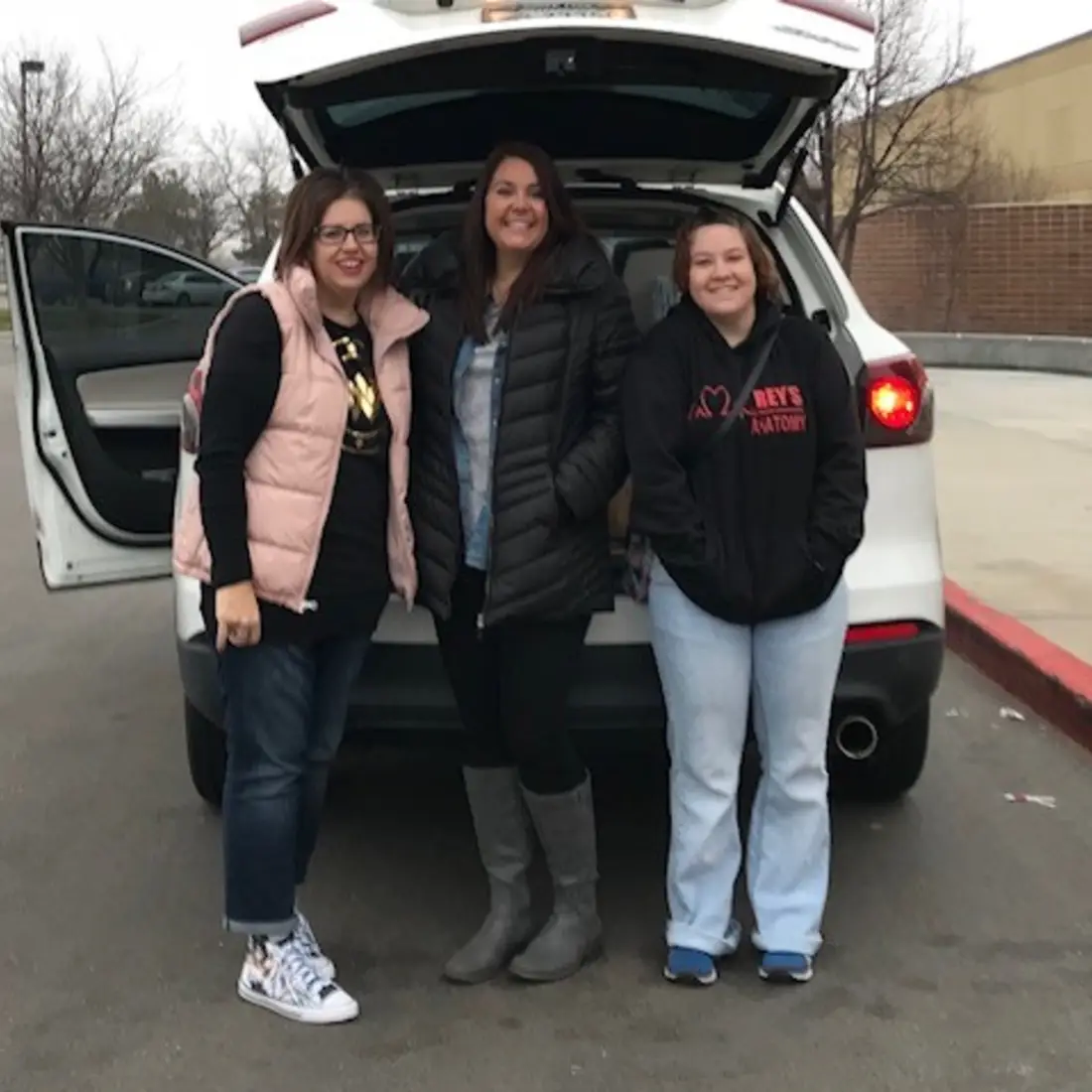 Criminal Justice Club students standing behind a white car