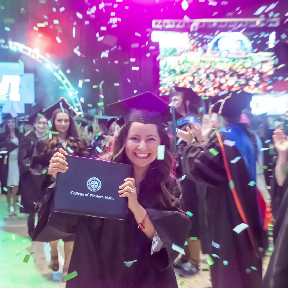 Graduate holding up diploma walking out of commencement