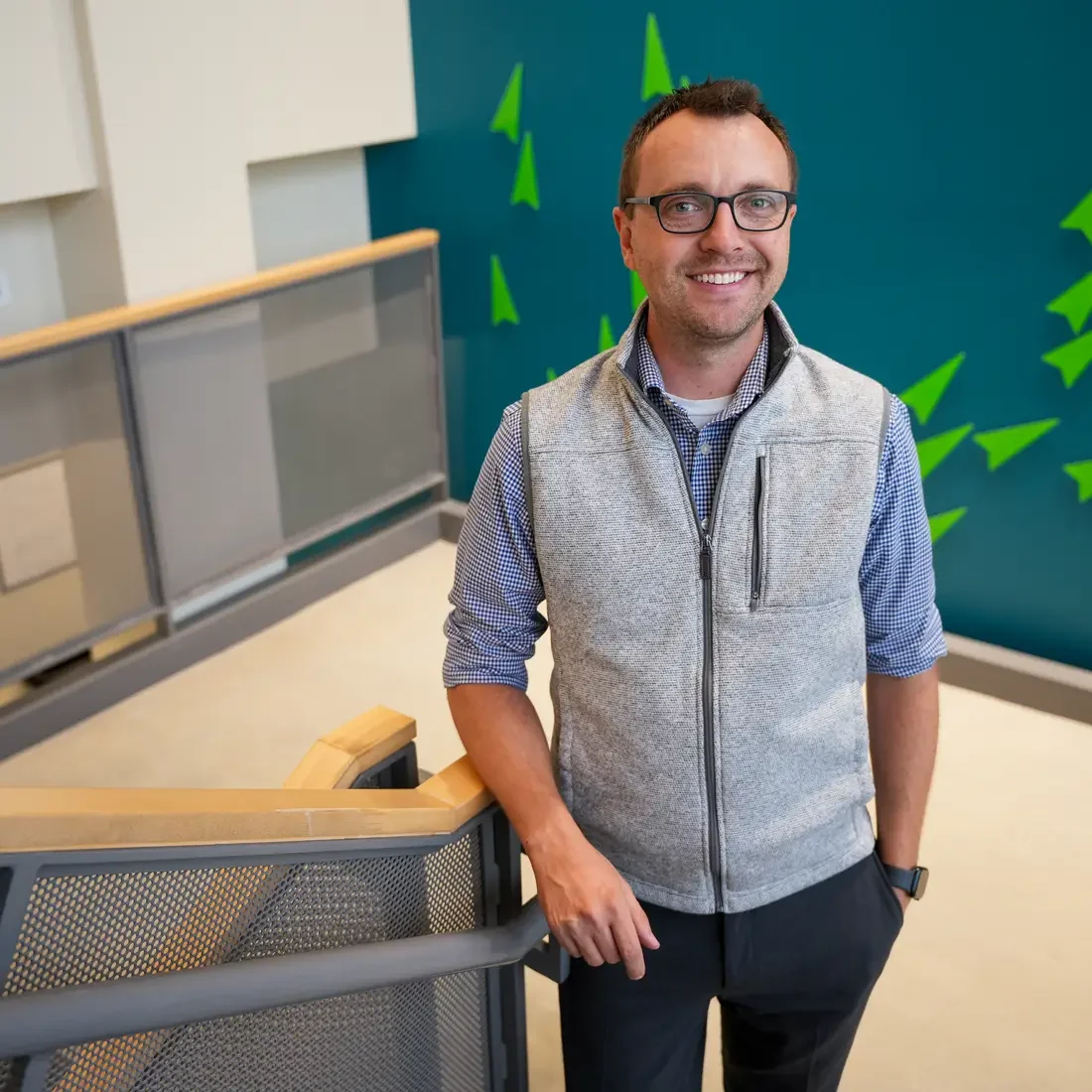 Cody Phelps stands in front of backdrop and near stair railing