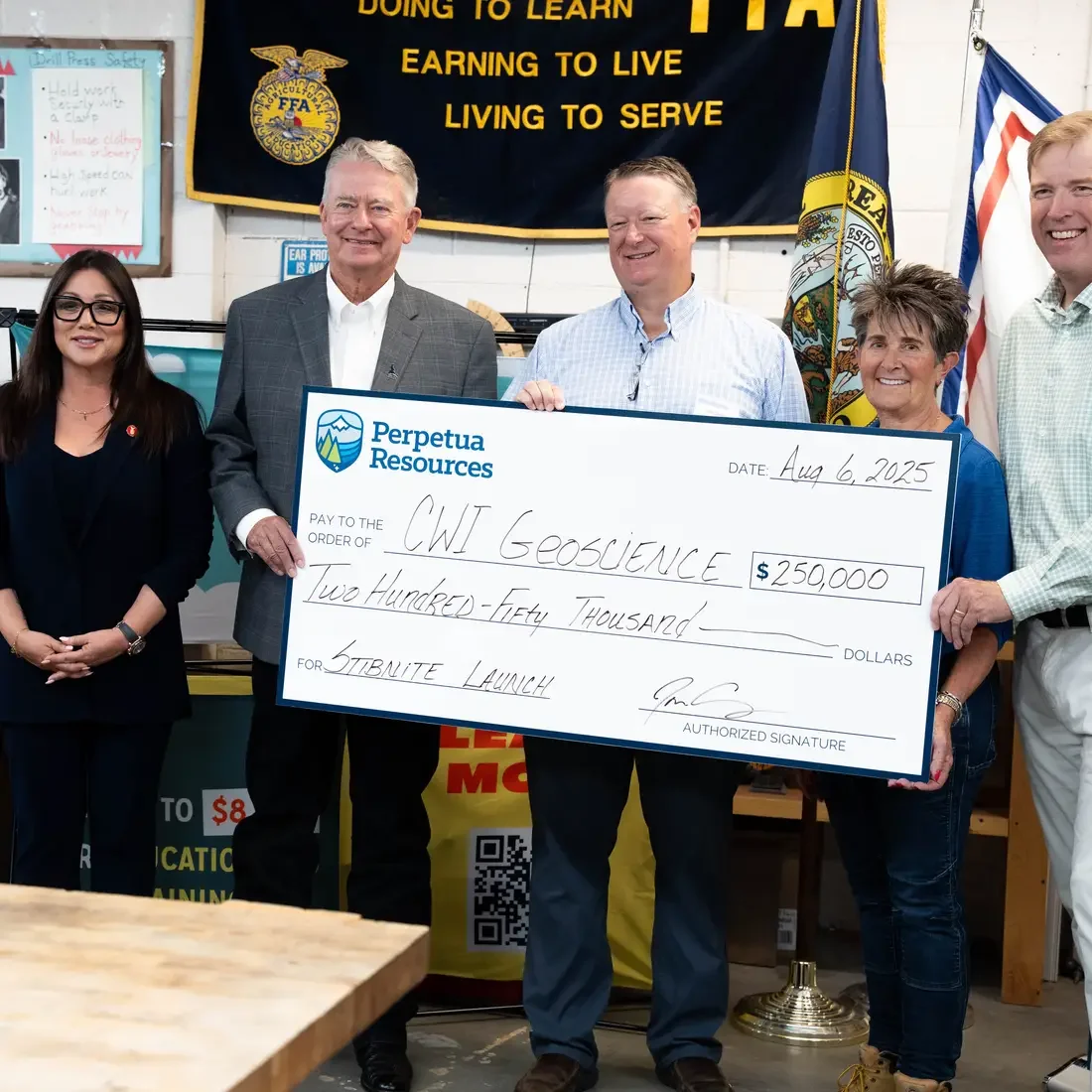 A group of people accept a ceremonial check donation for $250,000.