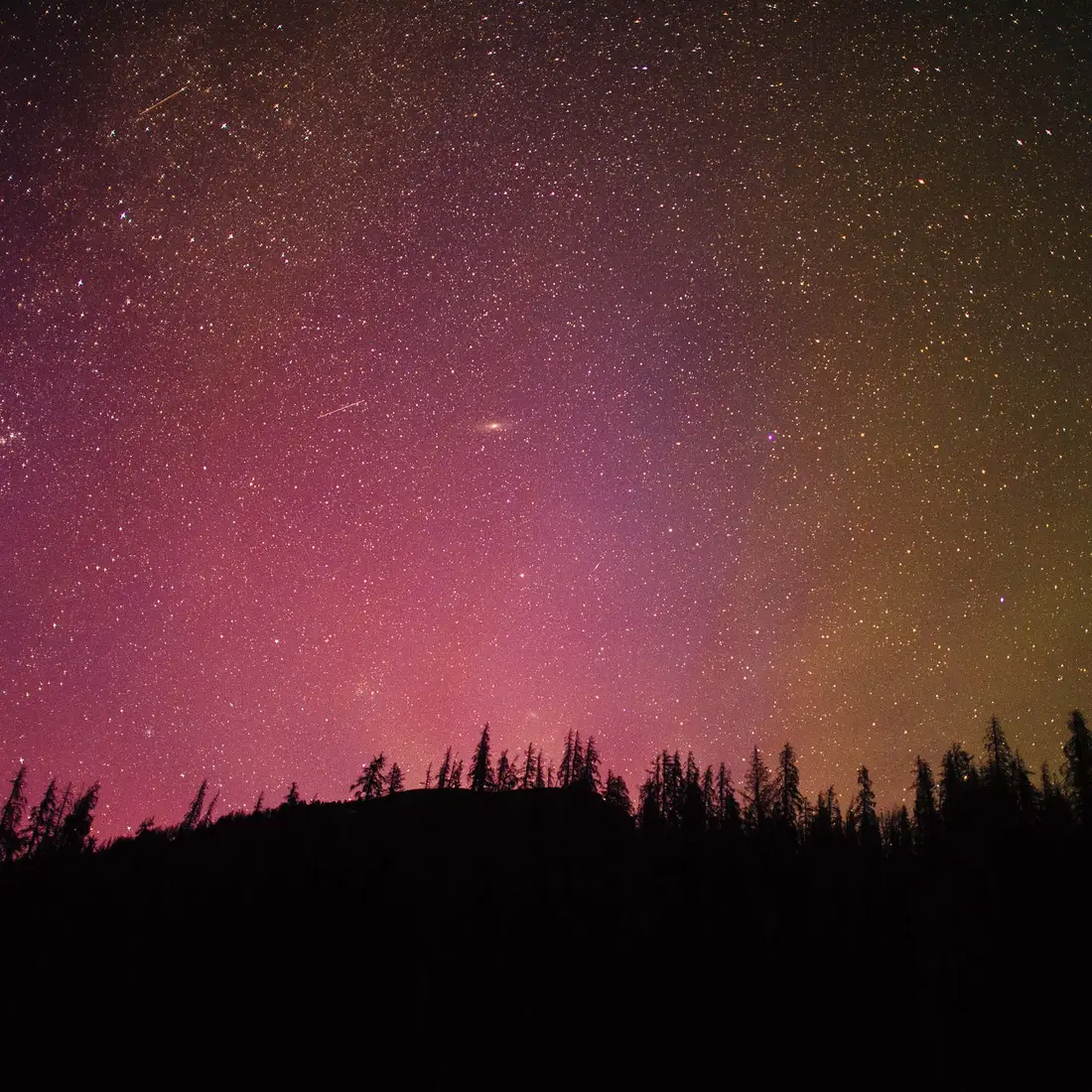 A photo of the night sky showing stars behind a silhouetted mountain top. 